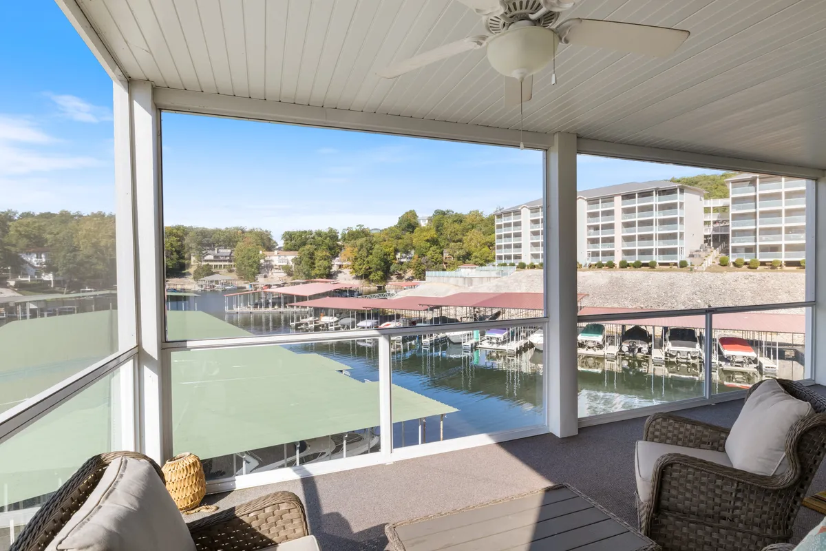 An inviting outdoor seating area overlooks the marina and docked boats, offering a peaceful setting for relaxing, socializing, or taking in the lake views. The scene captures the essence of lakeside living, with views of boats and the water promoting a sense of effortless adventure.