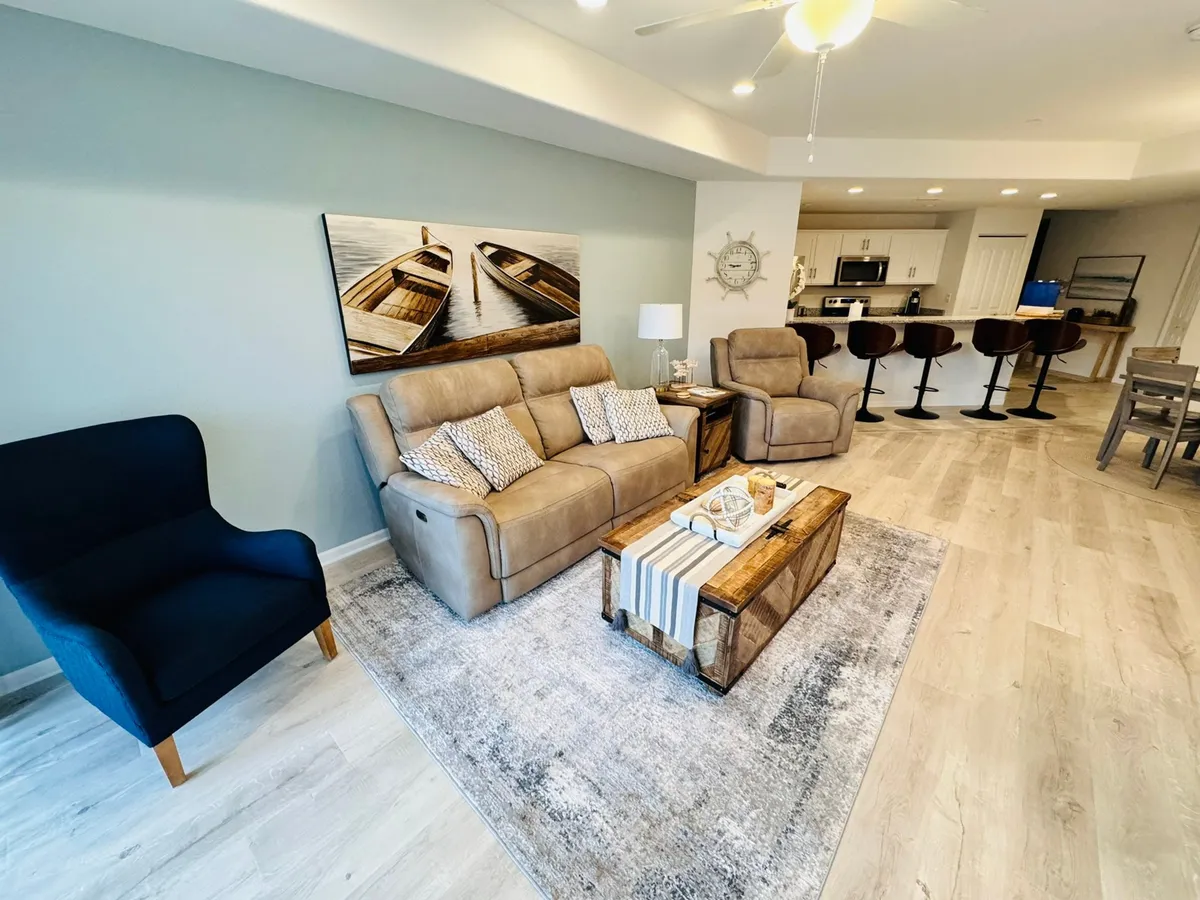 A comfortable and welcoming living area with a cozy sofa, rustic coffee table, and nautical-themed artwork. An inviting dark blue armchair sits nearby, creating an ideal spot for socializing or enjoying a quiet evening. The arrangement encourages conversation and shared experiences.