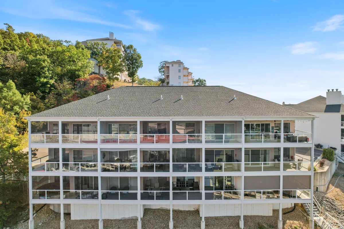 The image captures a multi-level balcony with sleek glass railings overlooking vibrant greenery. The setting is perfect for enjoying morning coffee or evening drinks while taking in peaceful, scenic views.